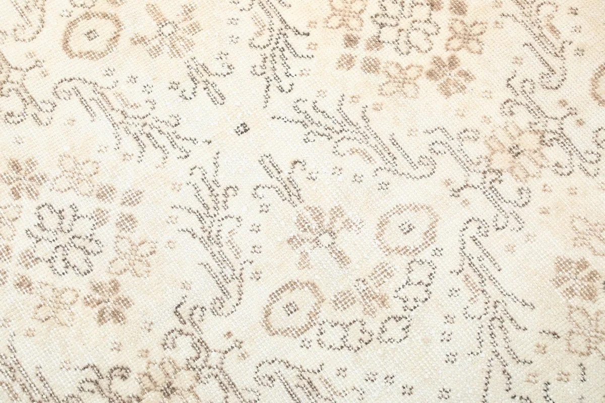 Close-up detail of the hand-knotted wool pile and the intricate tan and brown floral geometric motifs.