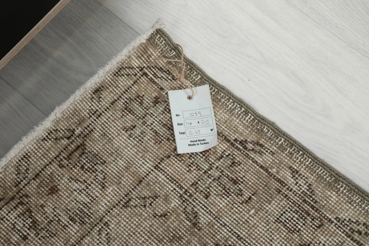 Rug corner with a product tag, showing details of the hand-knotted craftsmanship