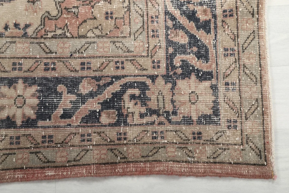 Corner detail of the rug showing the navy and beige floral border patterns
