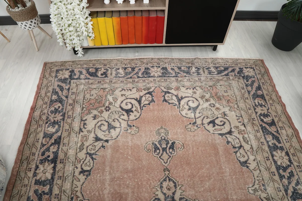 Overhead view of one end of the rose and navy rug in a room setting