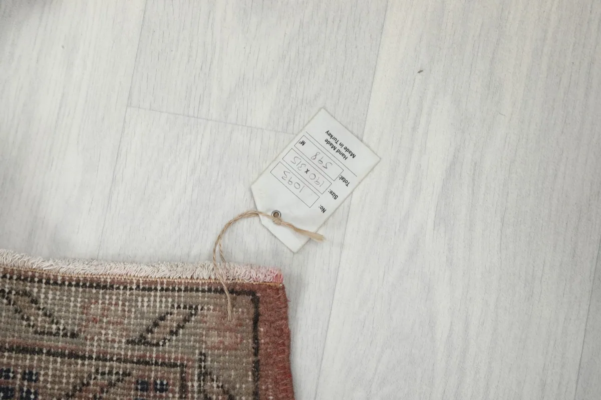 Small tag attached to the rug, indicating its details and origin
