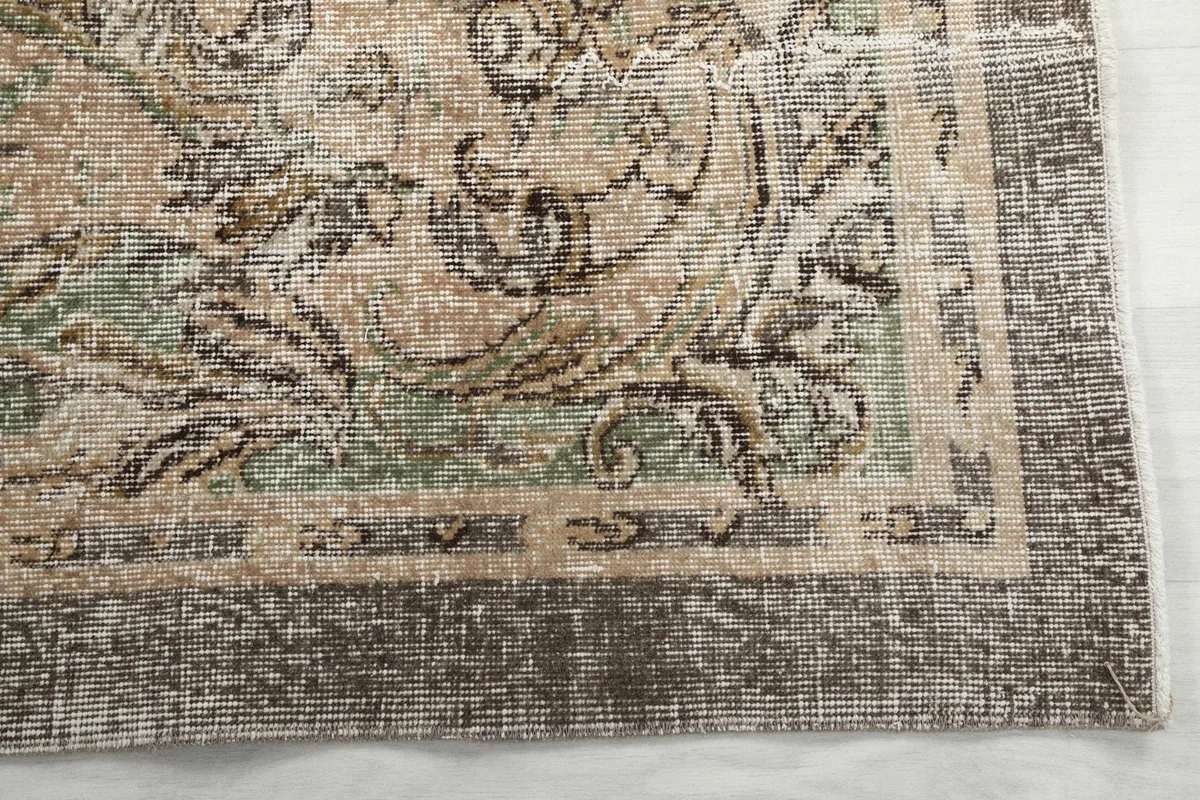 Detailed view of the rug's border and corner with distressed brown and beige tones