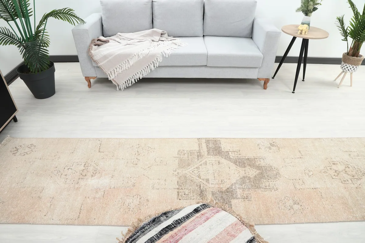 Overhead view showing the length of the beige runner rug in a room with a sofa