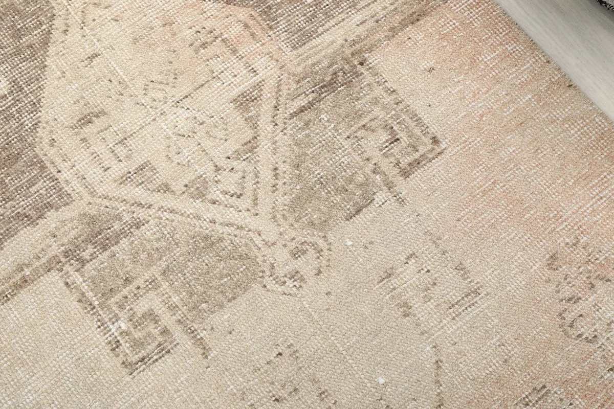 Close-up detail of the central geometric motif and the distressed pile of the vintage rug