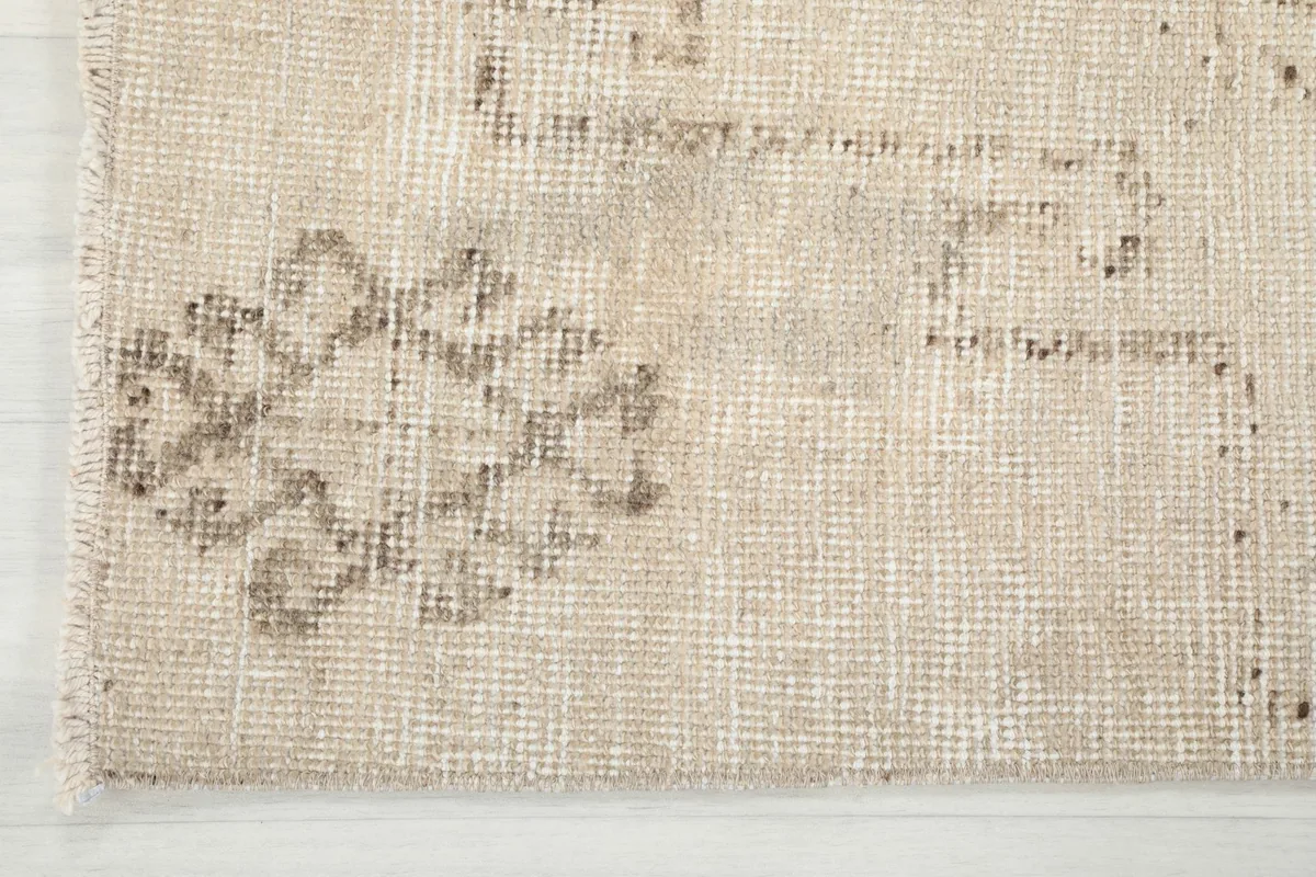 Detail of the rug's end showing a faded geometric element and the low pile texture