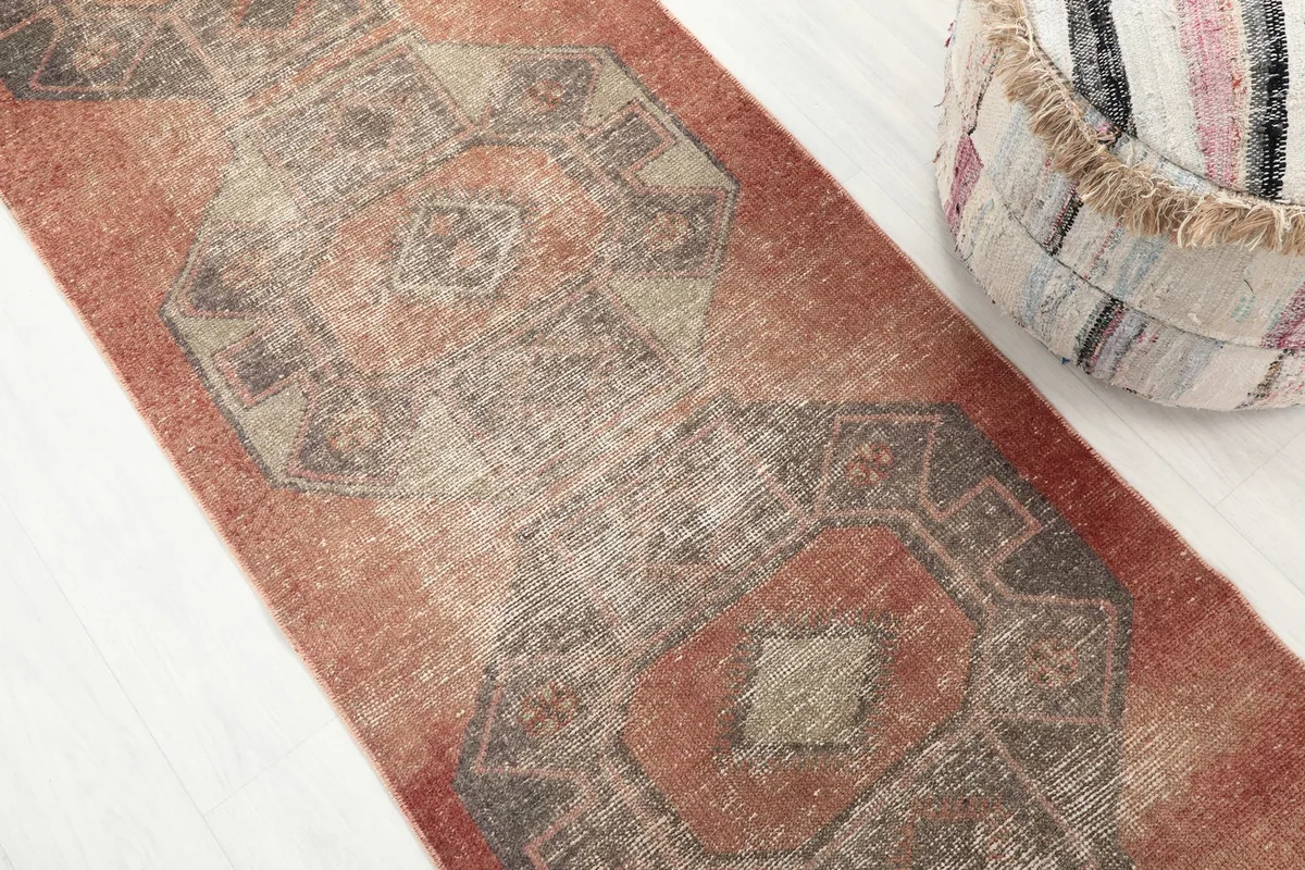 Angled view looking down the length of the runner, emphasizing the repeating charcoal and rust motifs.