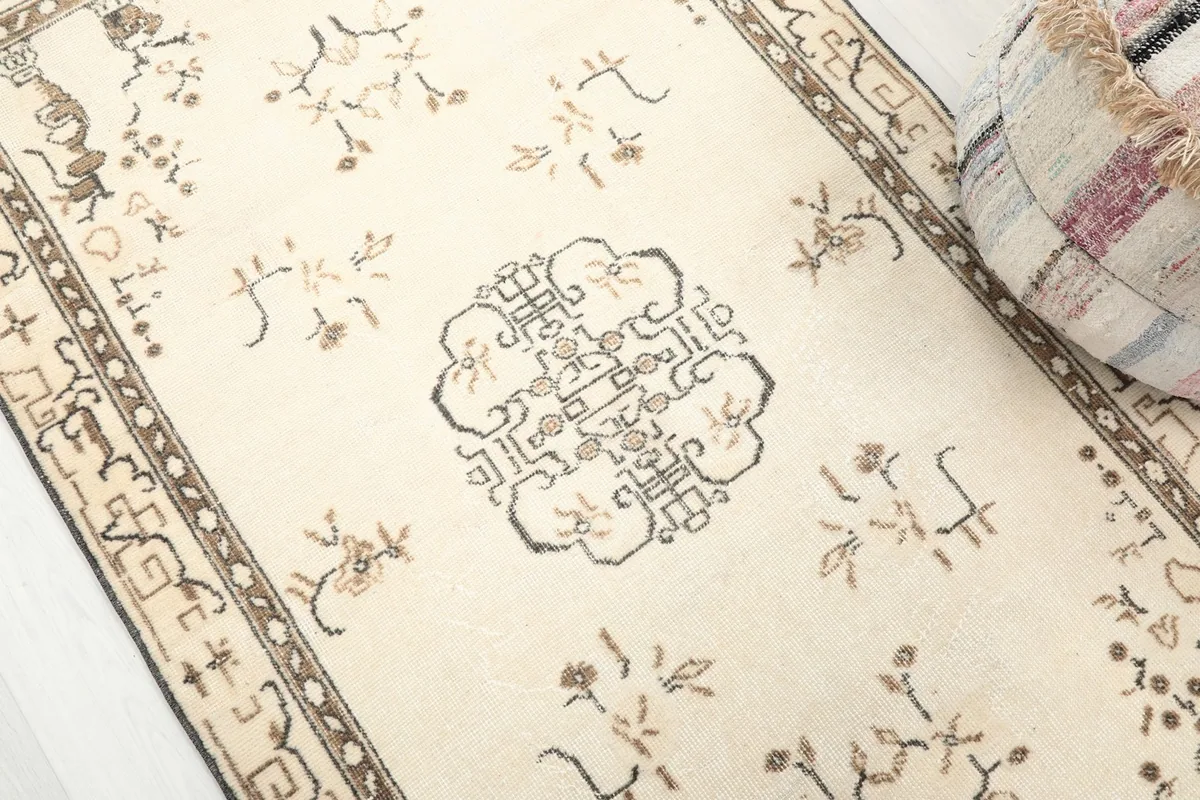 Close-up of the rug's ivory field and brown geometric medallion with subtle wear