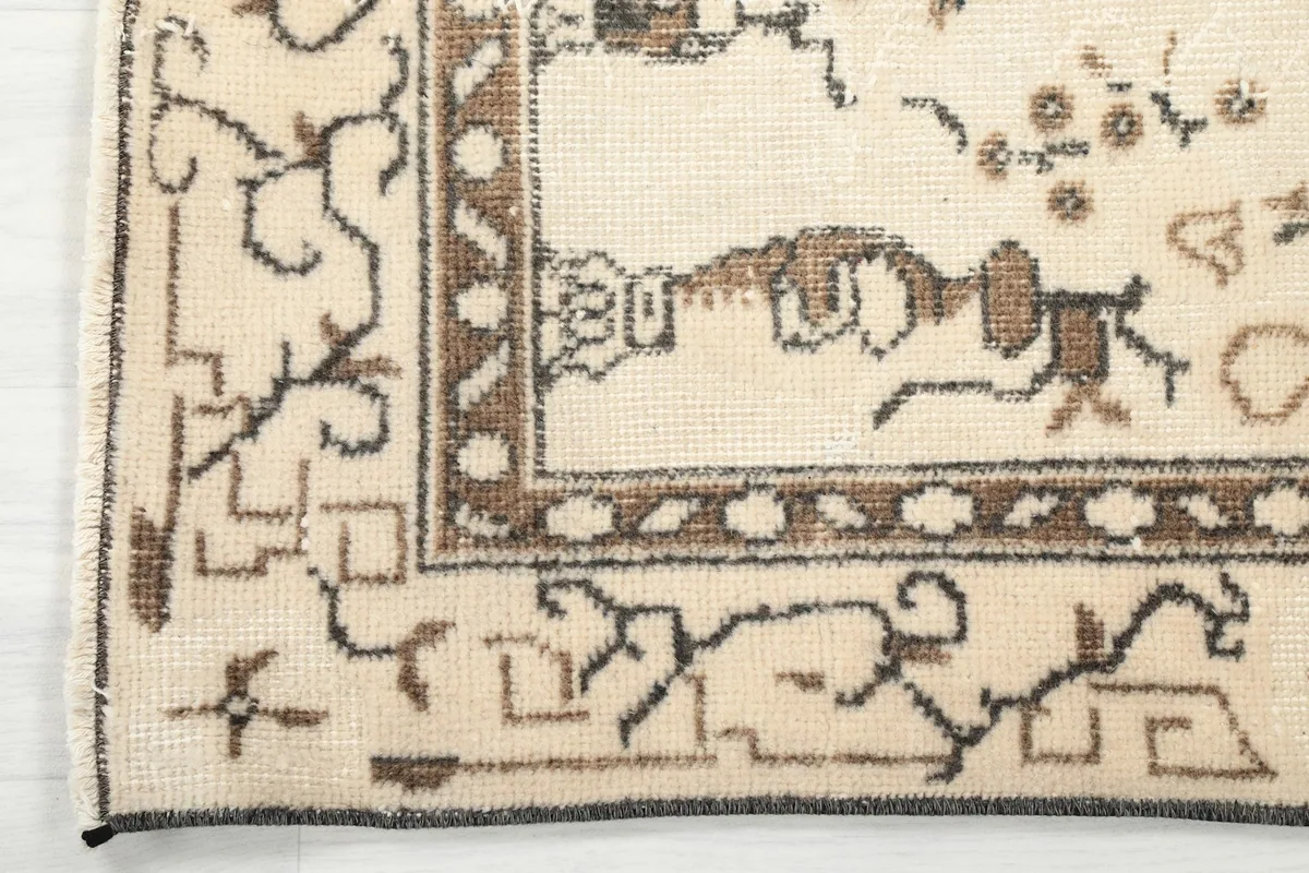 Corner detail of the rug, showing the brown border design and outer edges