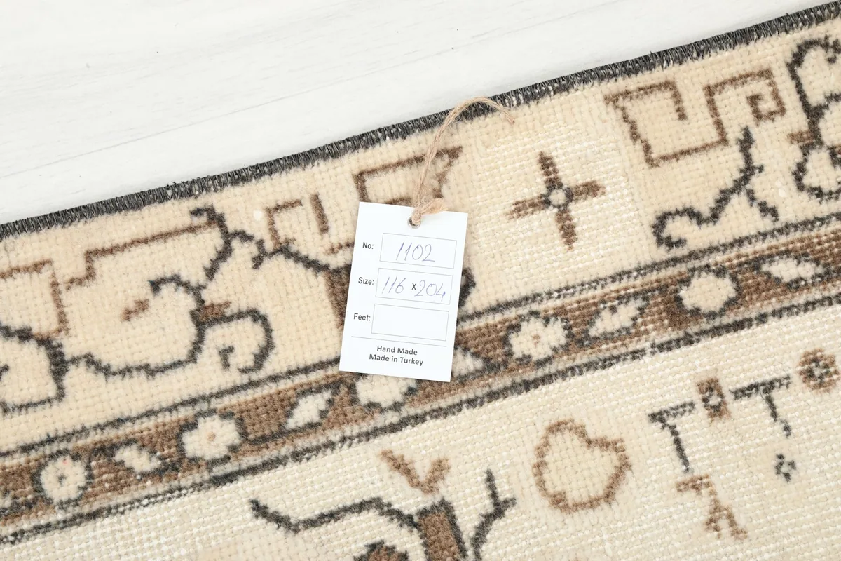 Close-up of the rug with a tag displaying its dimensions and origin, showing a border detail