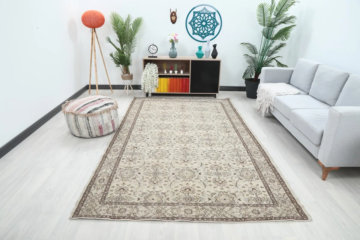 Beige floral Anatolian rug styled in a living room with a gray sofa and modern decor.