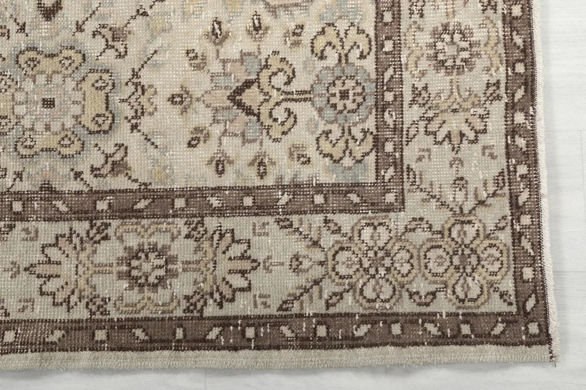 Detailed view of the corner of the rug, highlighting the floral motifs and brown border.