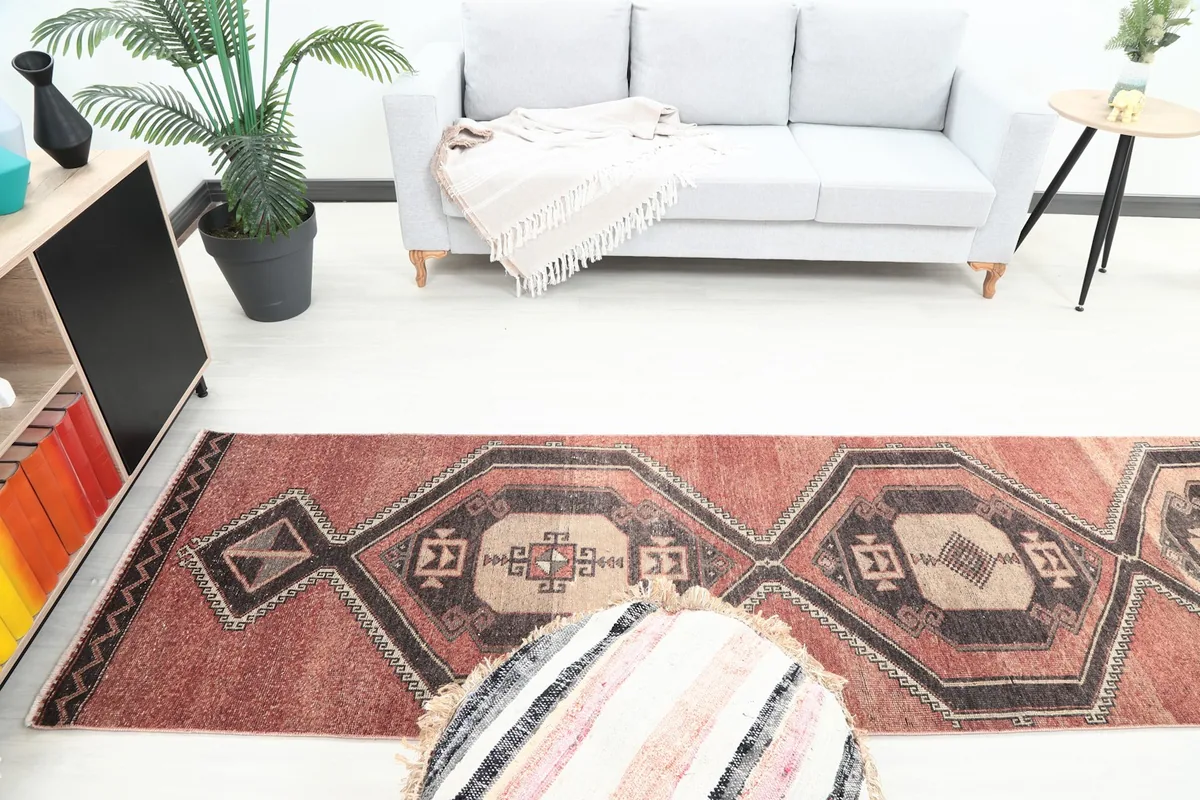 Overhead view of the vintage rust runner rug in a living area, displaying its full length and tribal motifs.