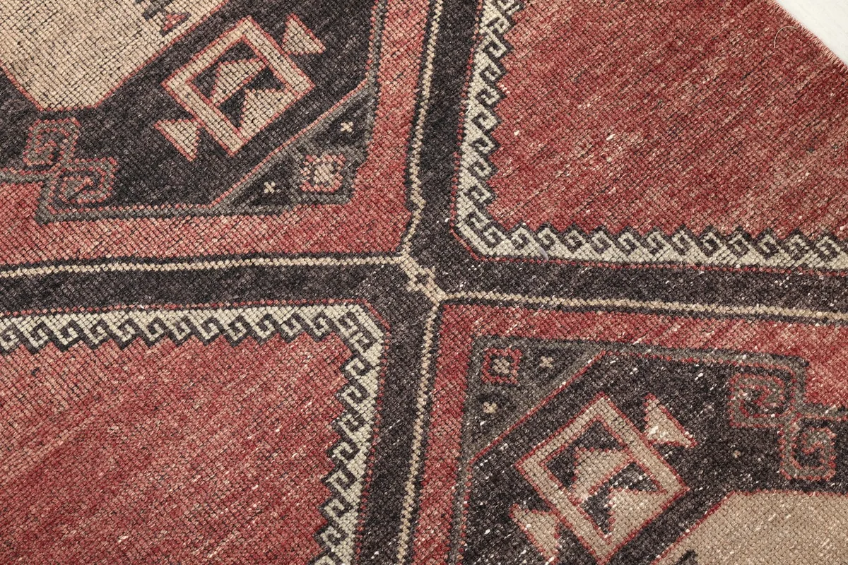 Close-up of the hand-knotted wool pile and the intricate geometric patterns with black and beige accents.