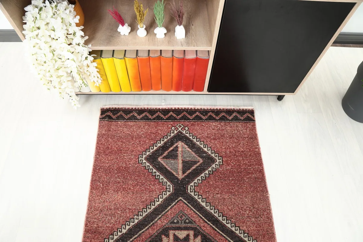 Overhead shot of one end of the rust runner rug, focusing on the intricate geometric design and border.