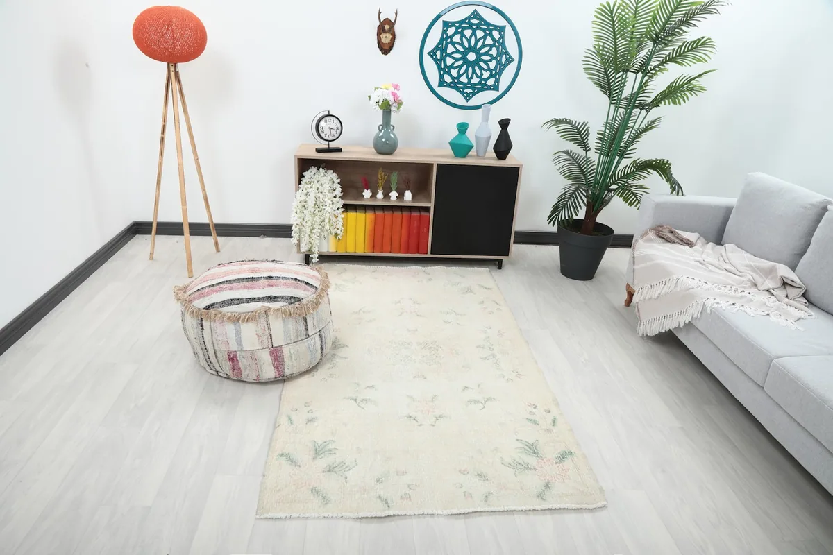 Ivory floral rug in a living room setting with a sofa and pouf