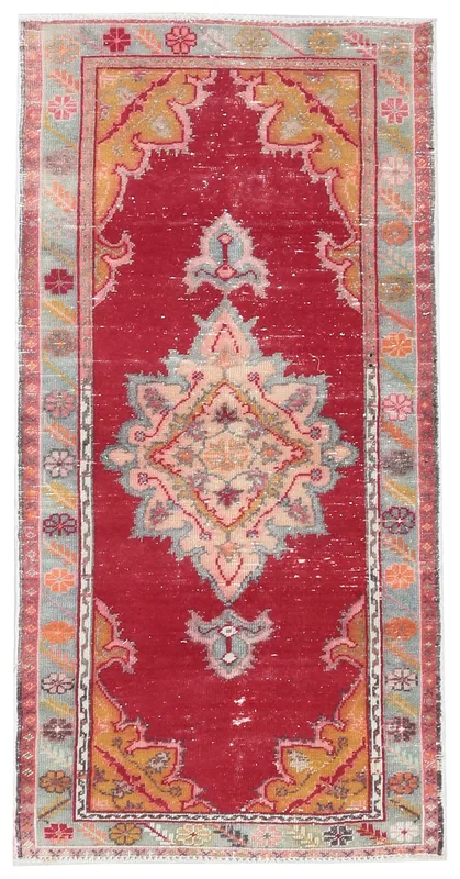 Full overhead view of a vintage red Anatolian rug with a central medallion on a white background