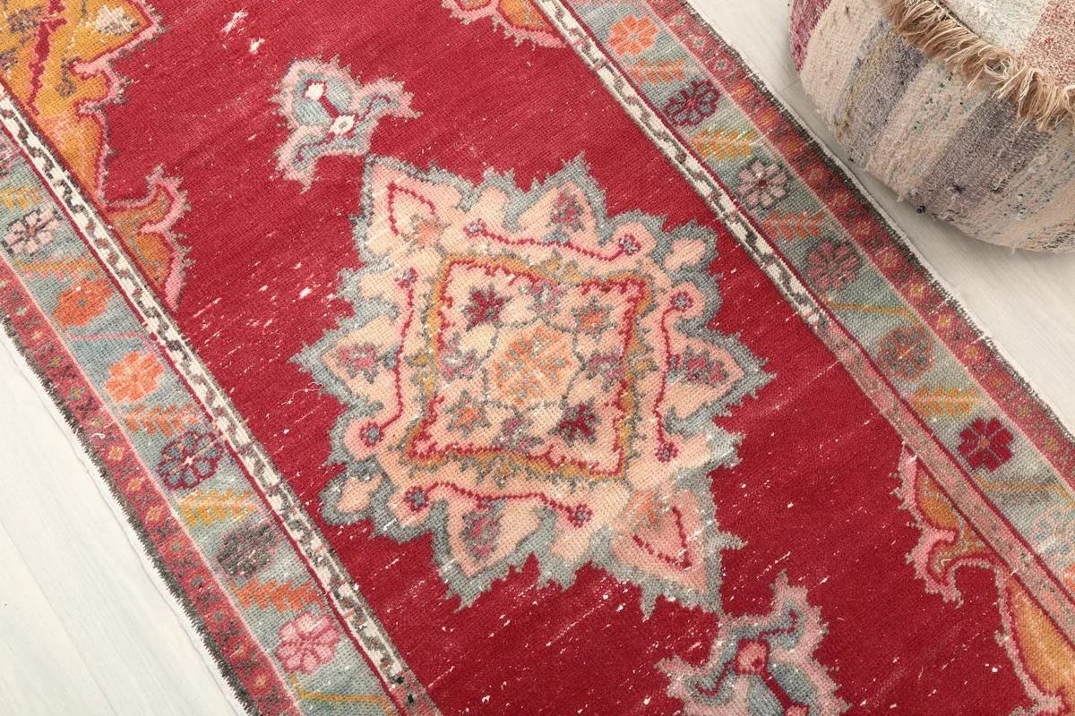 Close-up detail of the central medallion and surrounding patterns on the red rug