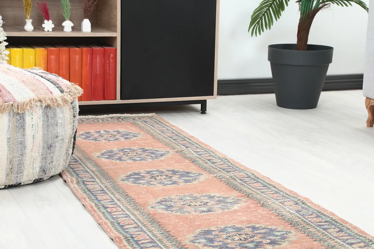 Close-up view of the rust runner rug's pattern and colors in a room setting, near a striped ottoman