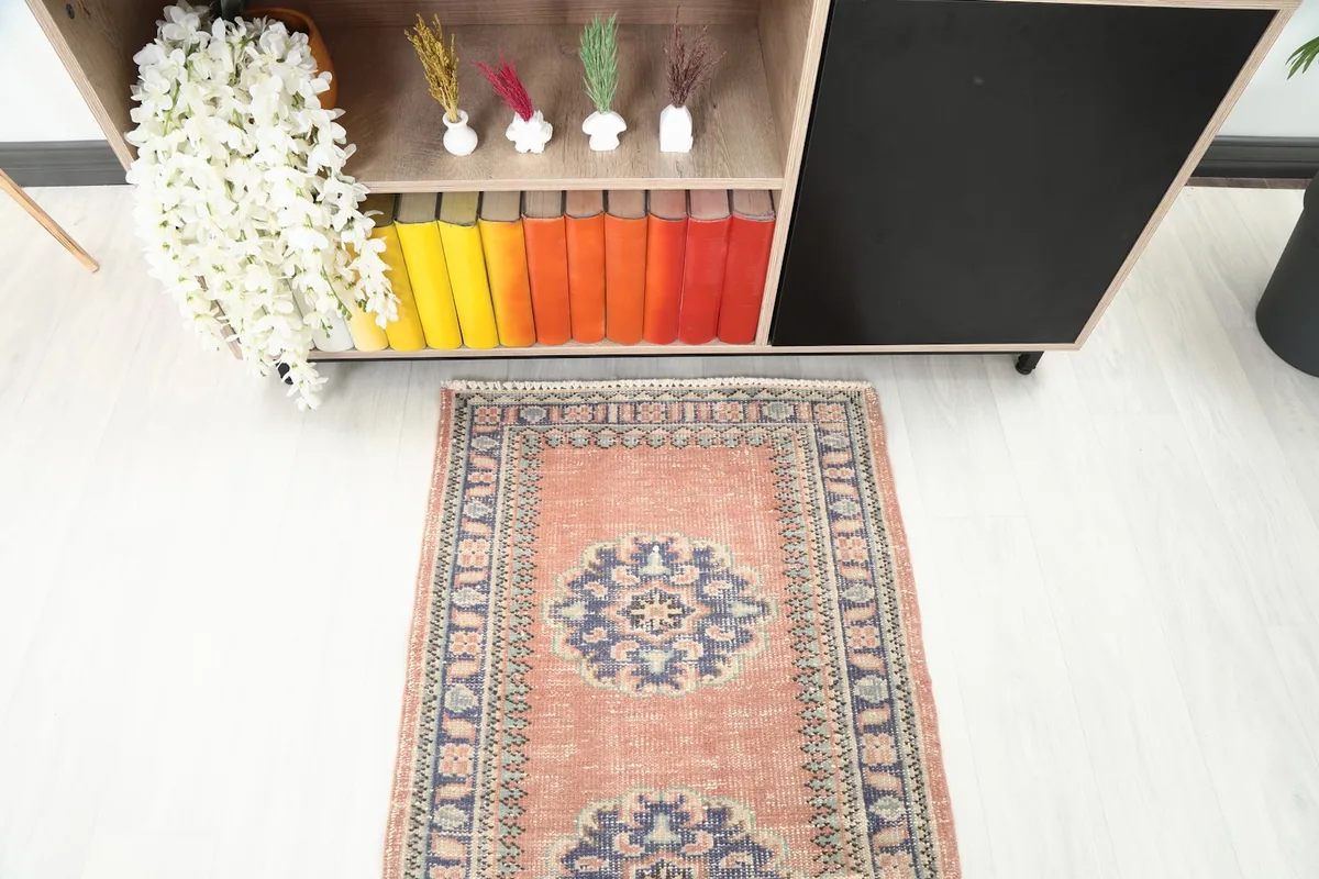Partial overhead view of the rust runner rug, showing its end section near a shelving unit with colorful books