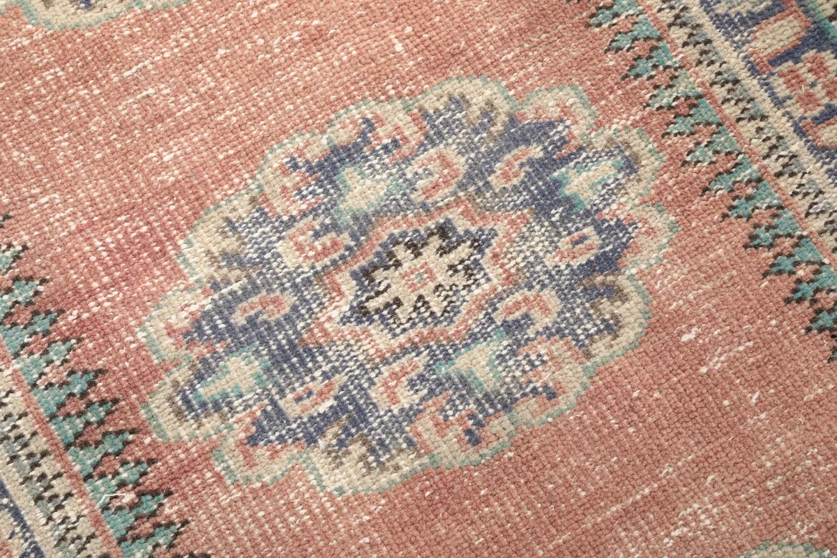 Detailed close-up of a blue medallion motif on the rust field, showing the intricate hand-knotted wool pile