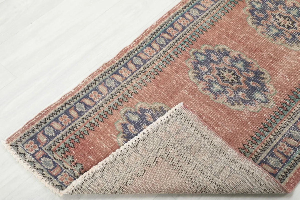 Corner of the runner rug folded back, showcasing the reverse side of the hand-knotted wool on cotton foundation