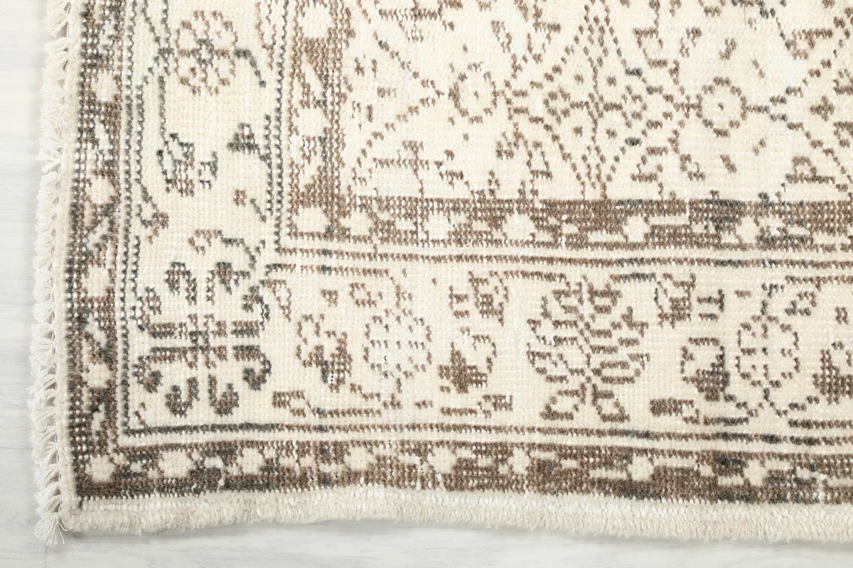 Corner detail showing the tan border design and the subtle fringe of the vintage rug