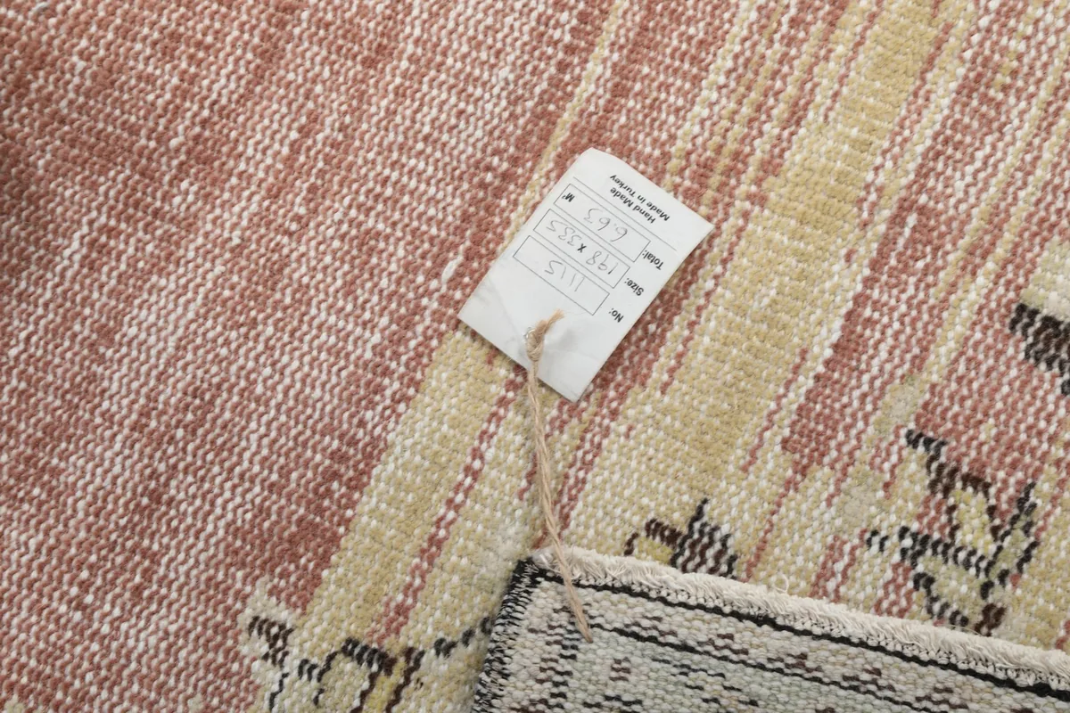 Detail of the rug's back and its woven texture, with a care tag attached