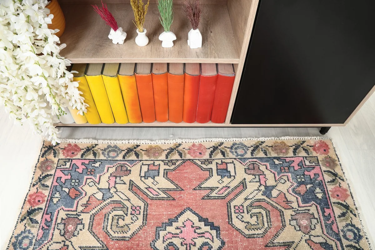 Detail of the rug's border and central design in a room setting, next to a cabinet.