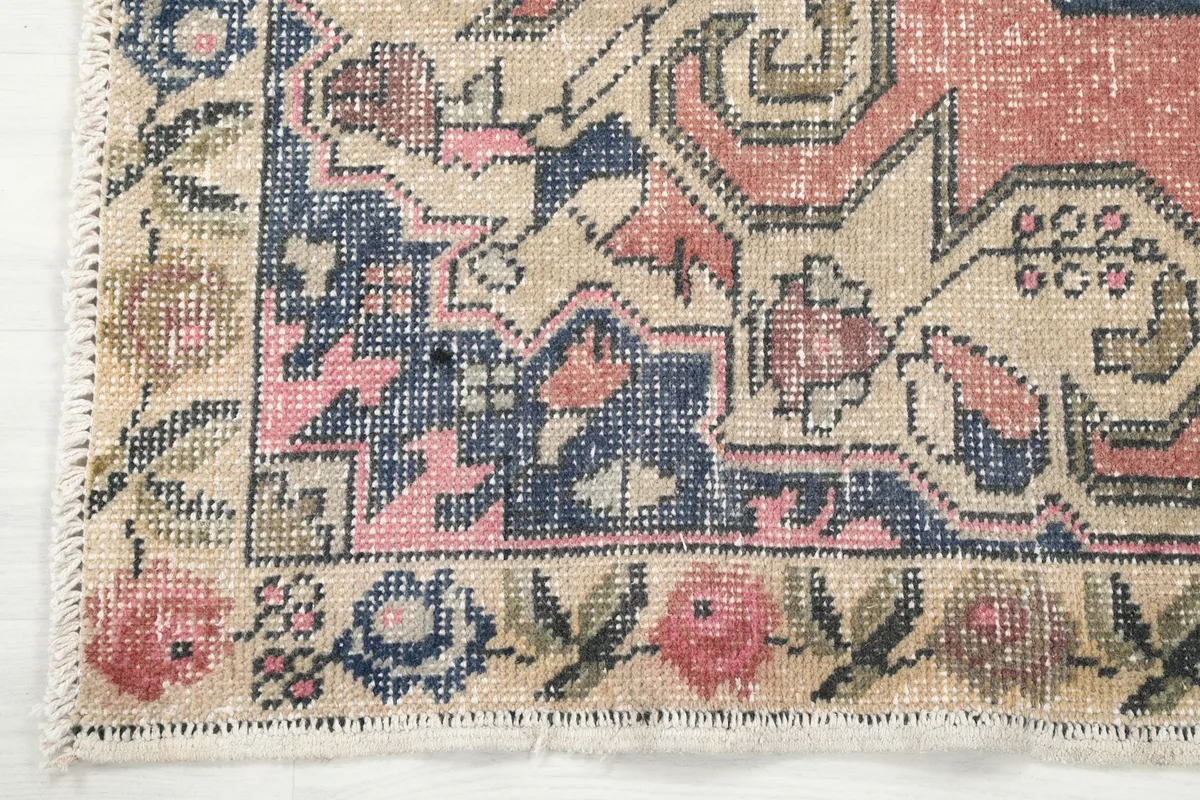 Close-up of the rug's border, showing floral elements and the fringe detail.