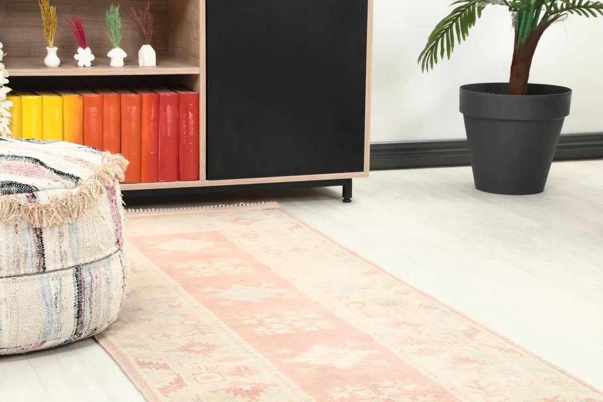 Close-up view of one end of the runner in a room, next to a pouf and a bookshelf.