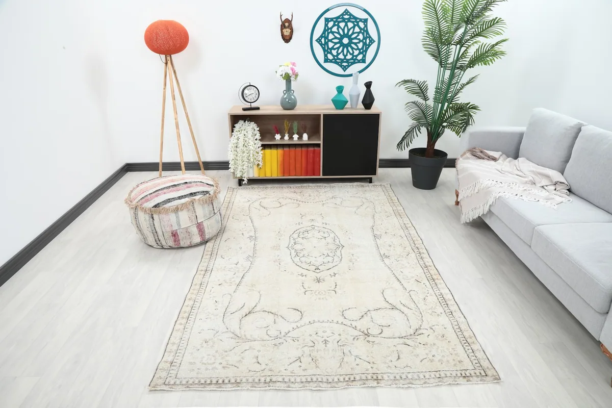 Ivory vintage rug displayed in a living room setting with a gray couch and wooden furniture.