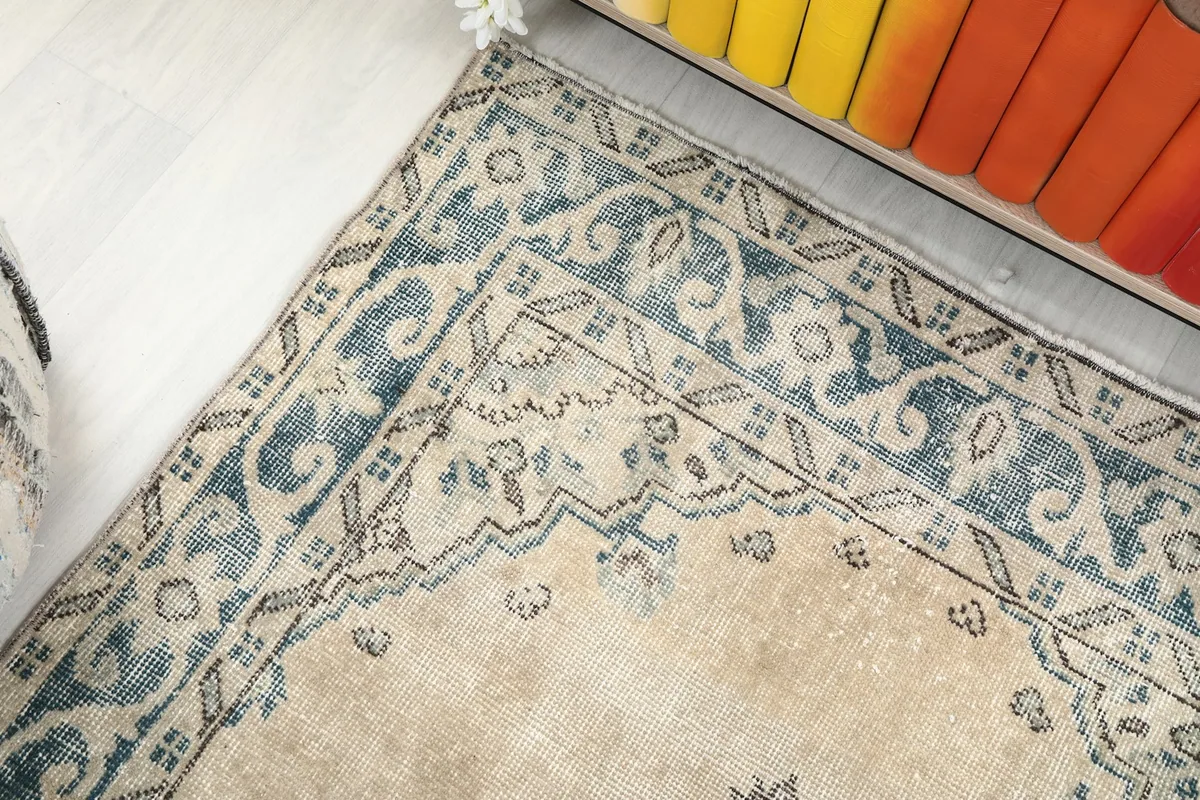 Detail of the rug's border pattern near a bookshelf, highlighting its colors.