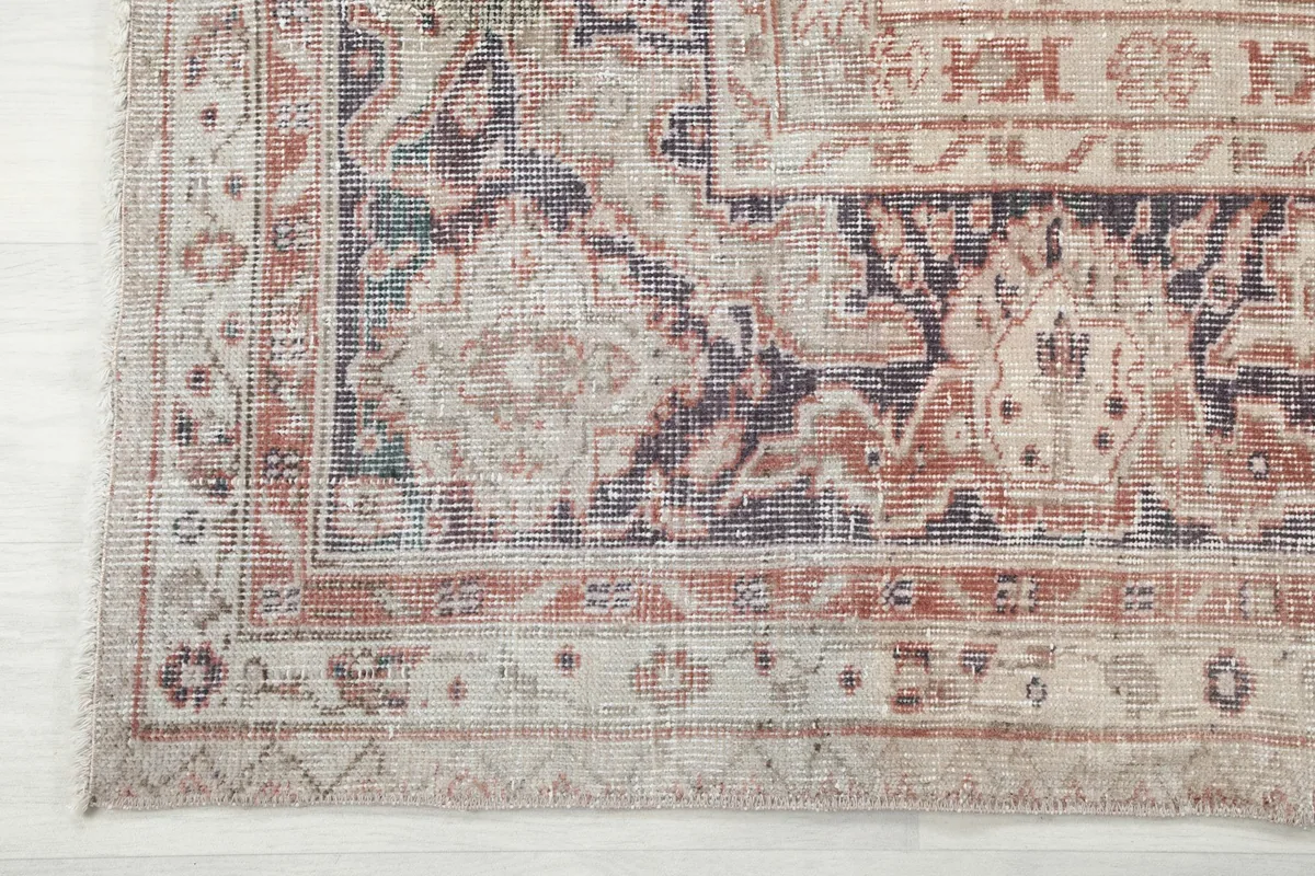 Detail of the rug's border showing a blend of rust, navy, and beige geometric patterns