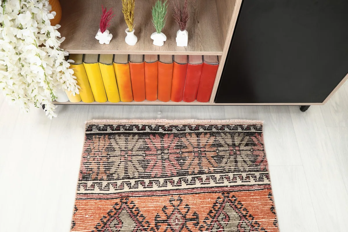 Detail of one end of the runner rug in a room, featuring black and rust patterns