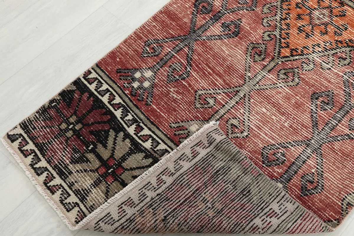 View of the rug's corner folded back, showing the back of the rug and the pile