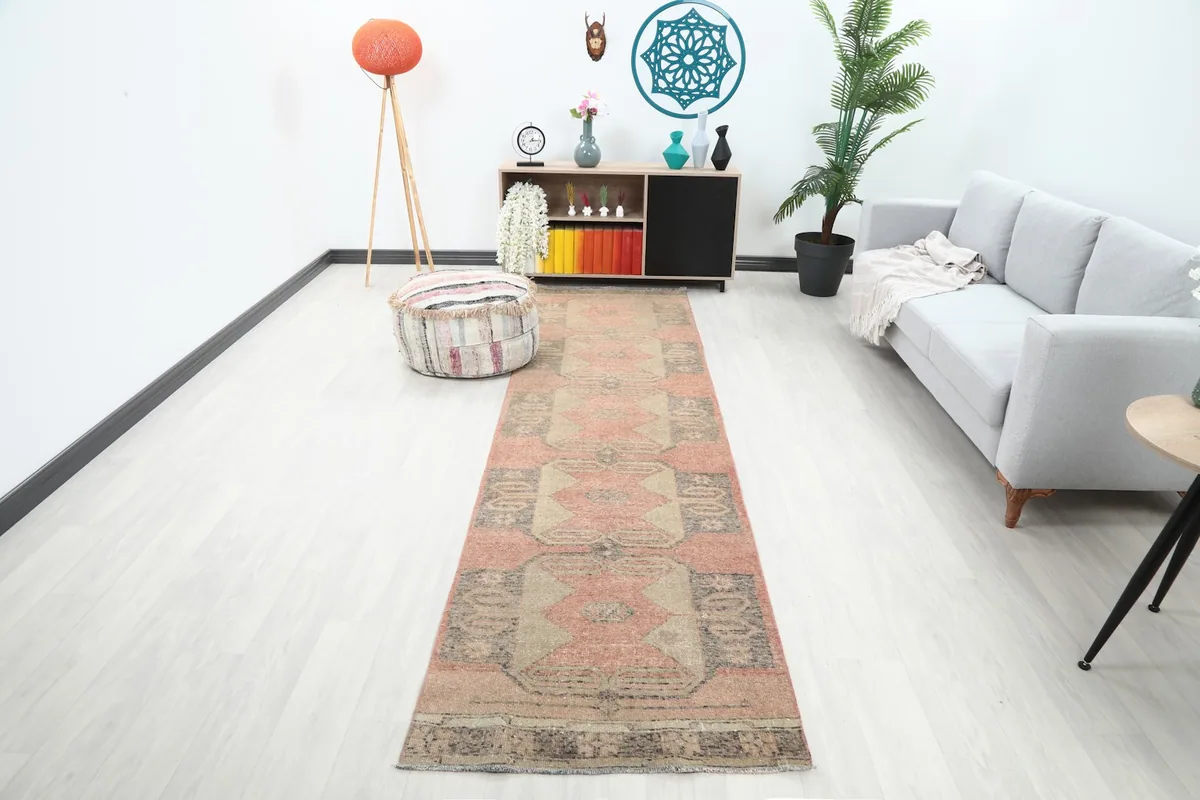 Vintage runner rug in a living room setting, showcasing its length and rose, beige, charcoal colors.