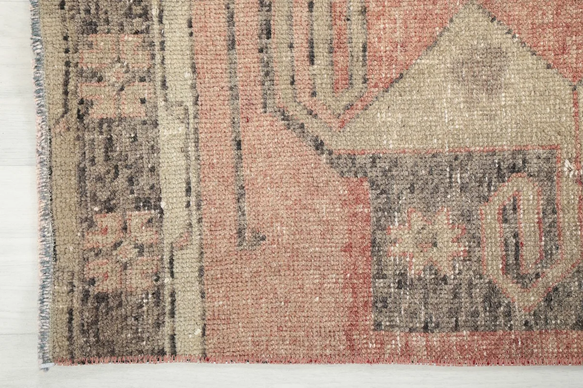 Detailed view of the rug's end, showing the short fringe and the distressed edges.