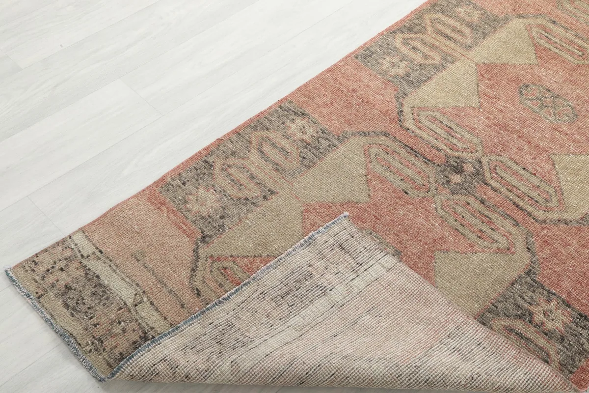 Corner of the runner rug folded back, showing the wool pile on cotton foundation.