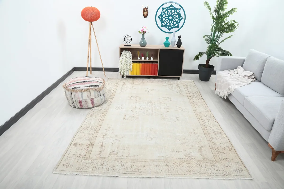 Vintage cream rug in a living room setting with a gray sofa and wooden furniture