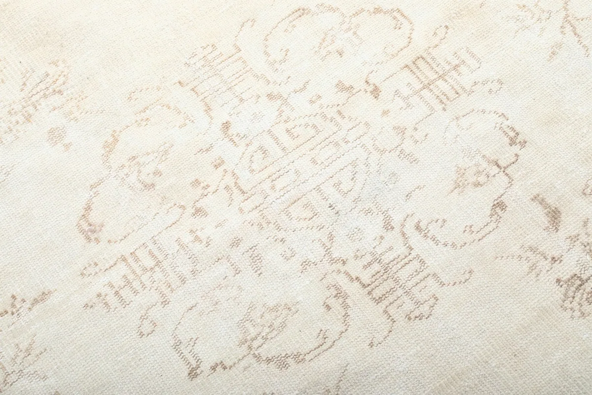 Close-up detail of the faded central medallion pattern on the cream rug