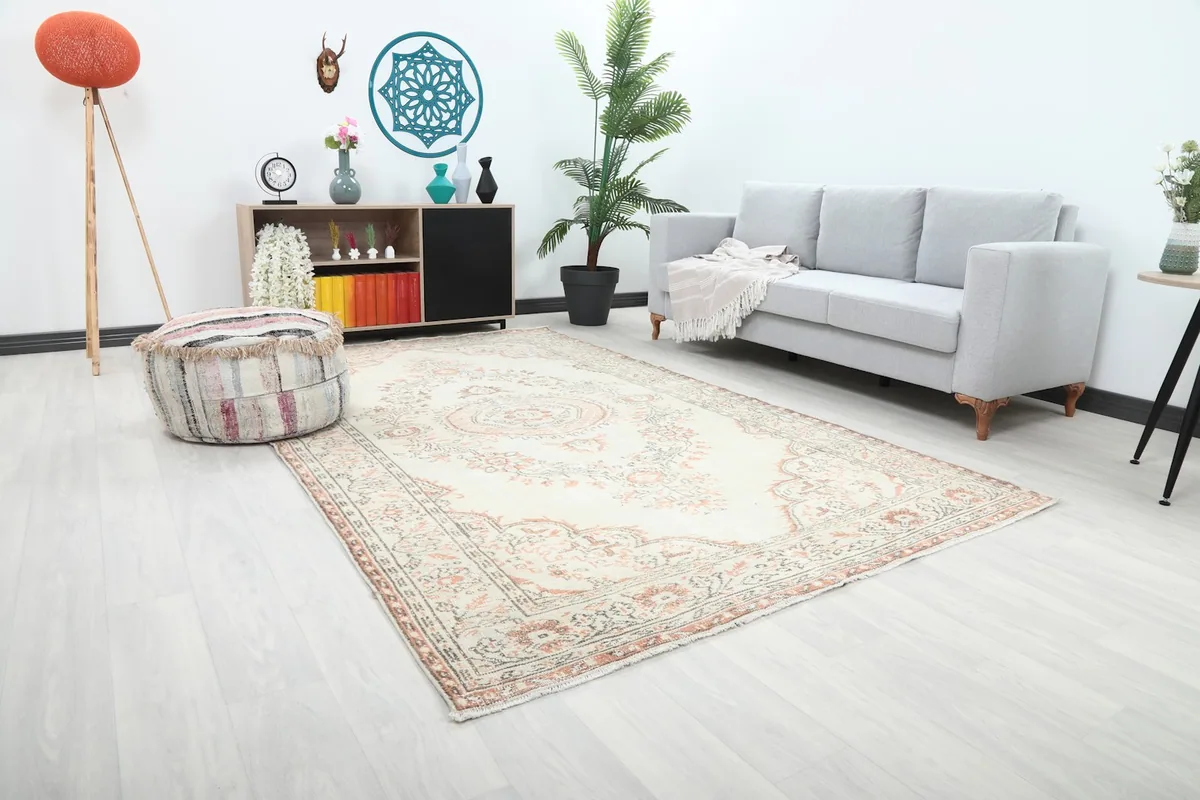 Angle view of the ivory and rust vintage Anatolian rug in a living space with light flooring