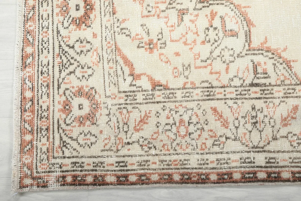 Close-up of the rug's border pattern with rust and brown details and subtle fringe