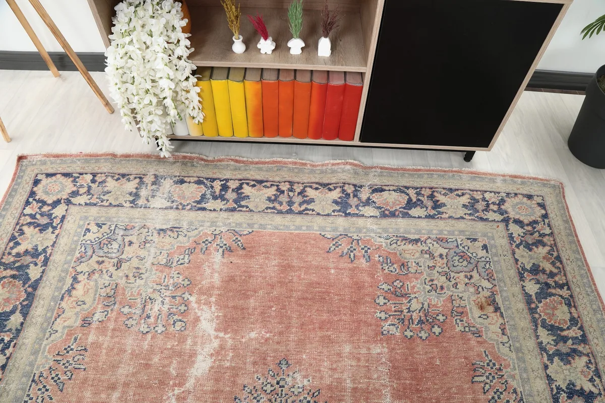 Detail of the rug's border and field patterns near a colorful bookshelf