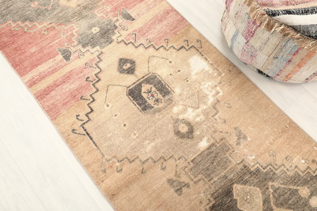 Close-up of the rug's central tribal geometric motifs and the varied rose and beige colors.