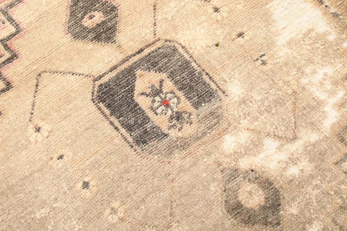 Detailed view of a specific tribal motif, showing the intricacy of the hand-knotted wool and signs of wear.
