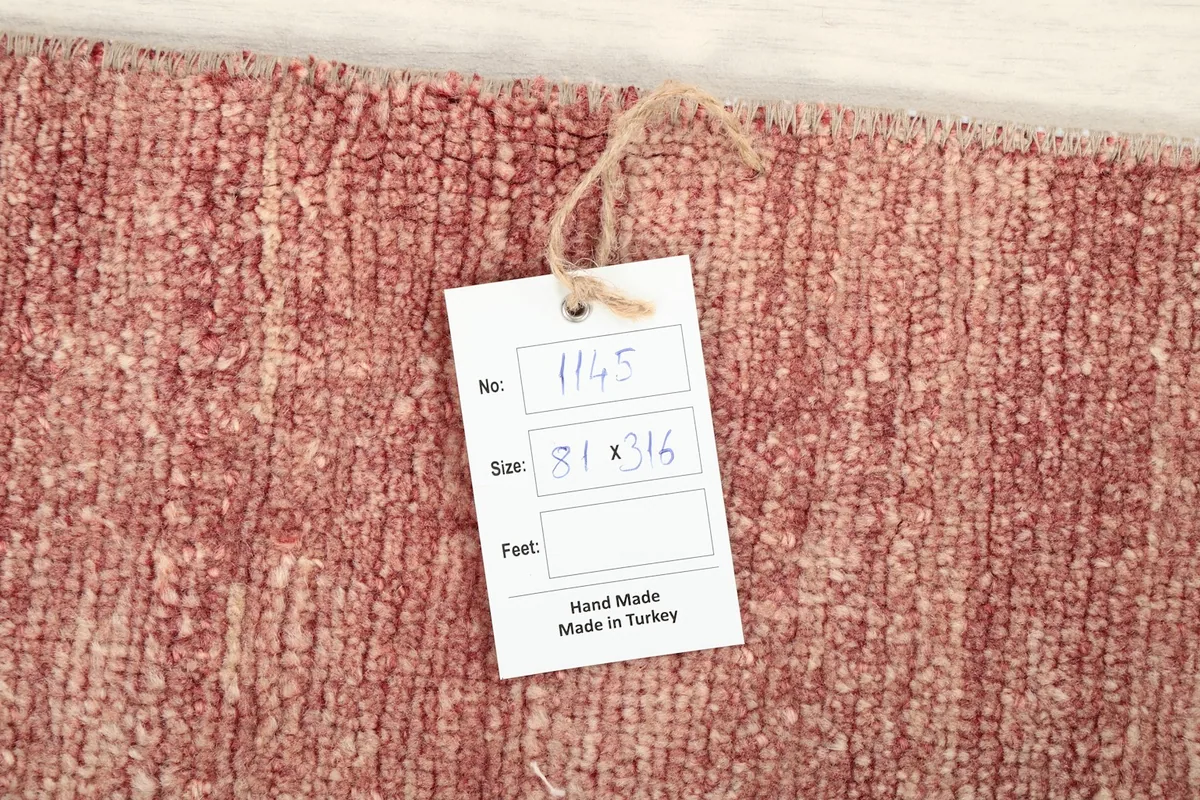 Close-up of the rug's surface with a tag indicating its dimensions and origin.