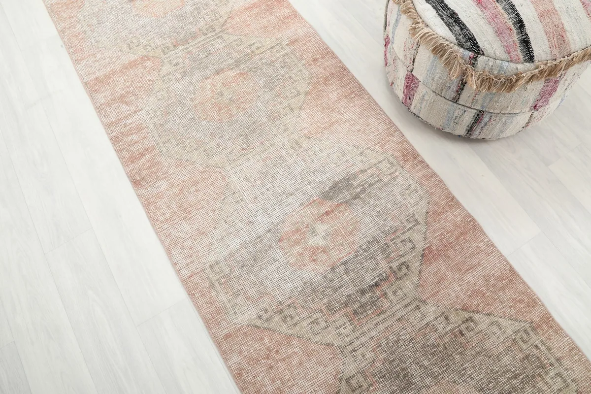 Side angle view of the long runner rug, highlighting its muted rose, gray, and beige tones