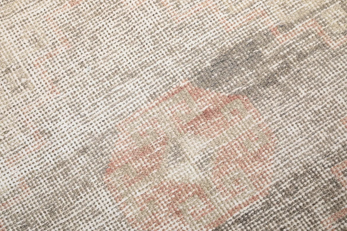 Close-up detail of the hand-knotted wool pile, showing the texture and faded rose and gray colors