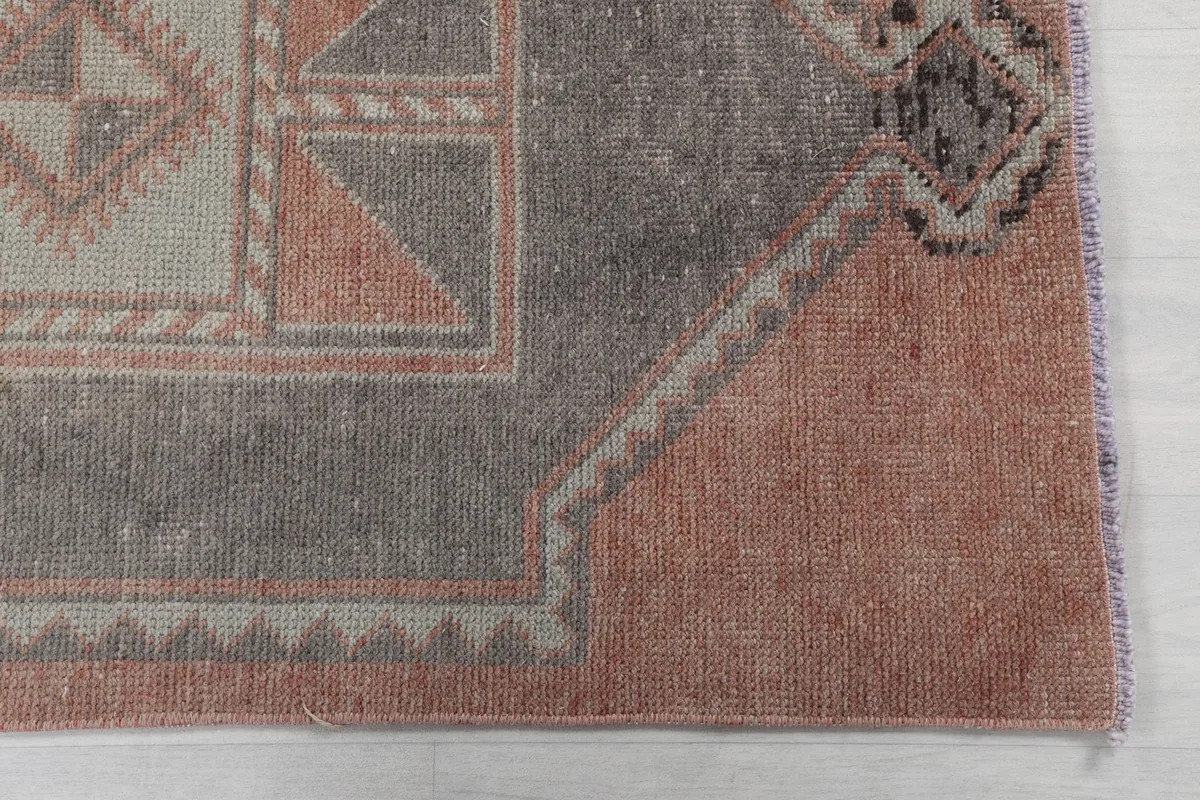 Detailed view of the rug's rust field and a gray geometric motif