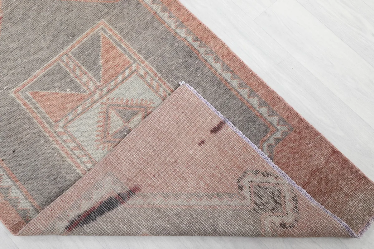 Corner of the rug folded to reveal the cotton foundation and reverse side